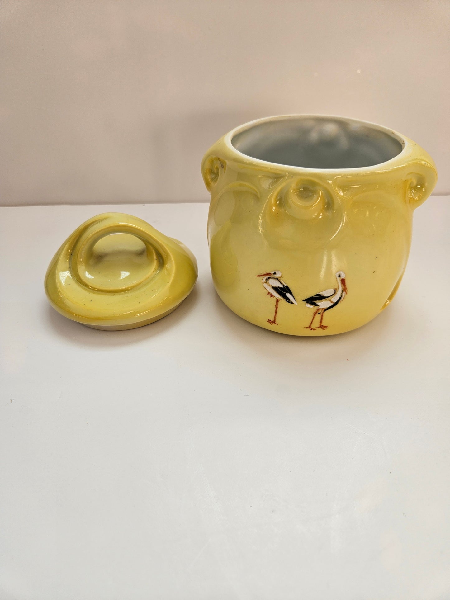 Two yellow ceramic items with a bird design on a white background
