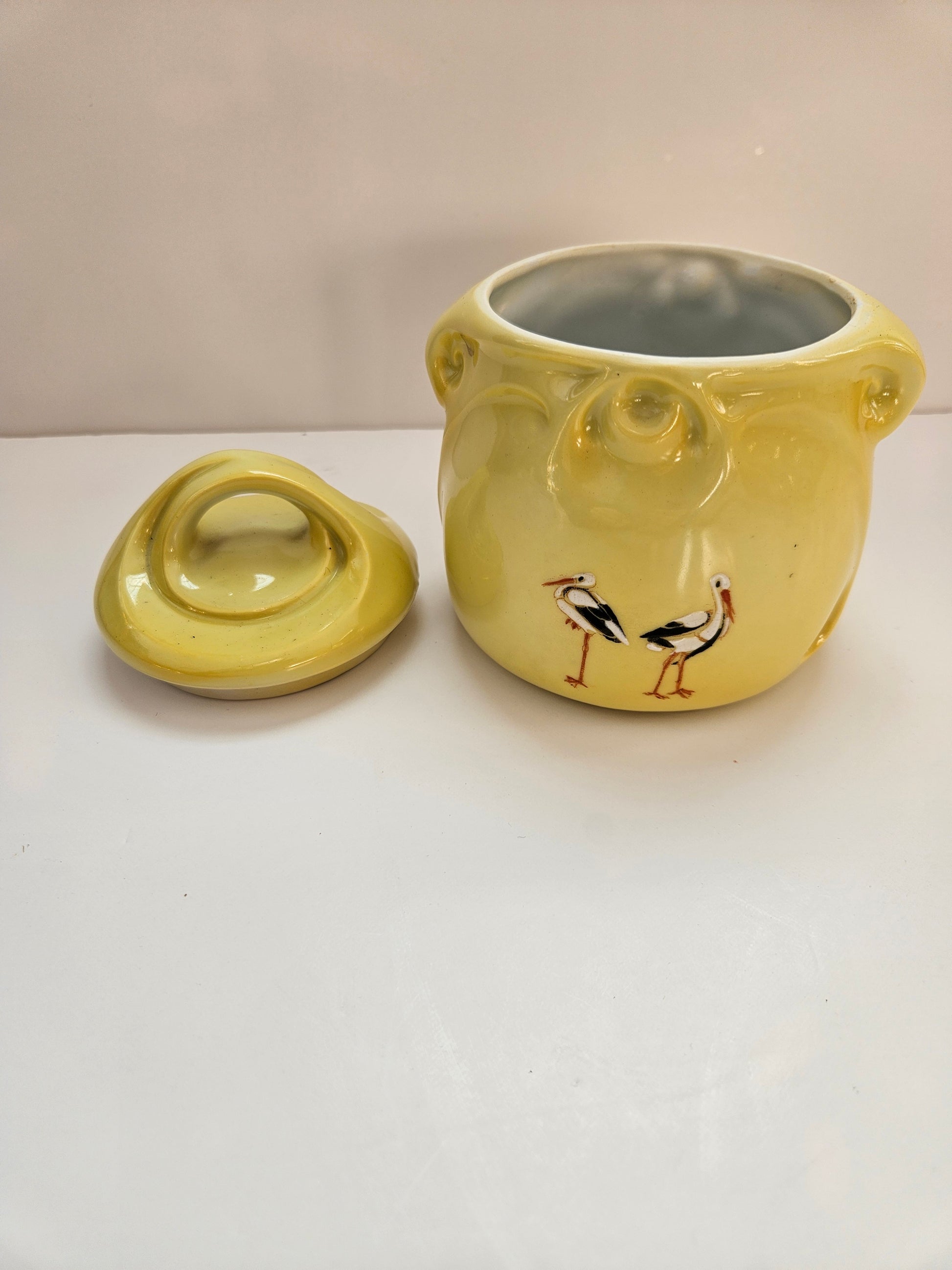 Two yellow ceramic items with a bird design on a white background