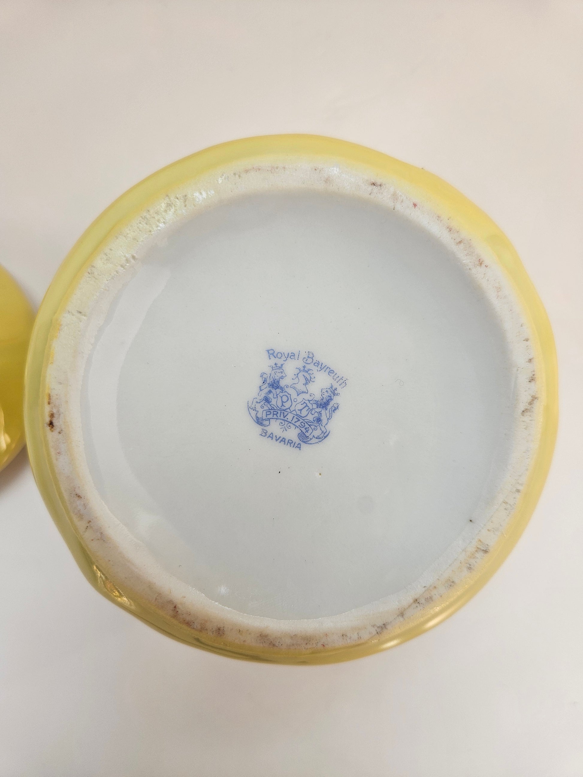 Close-up of a yellow-rimmed ceramic jar with a blue logo "Royal Bayreuth" on a white background